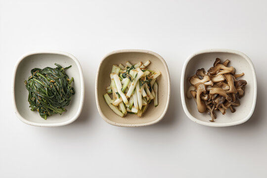 Assorted Asian appetizers: spinach, celery, mushrooms in ceramic bowls on a white background
