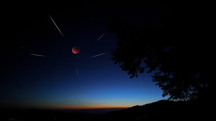 Fototapeta premium Blue hour time with lunar eclipse, stars and planets above landscape silhouettes.
