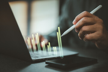 Business person analyzing digital bar chart graph on laptop with stylus pen