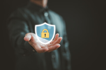 Businessman holding glowing shield with lock icon representing digital security and data protection