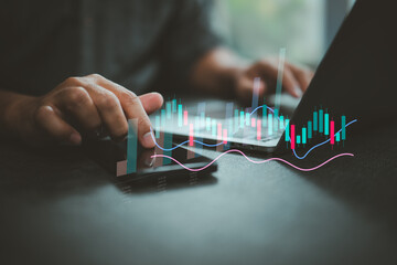 Analyzing financial data with smartphone and laptop showing stock market charts