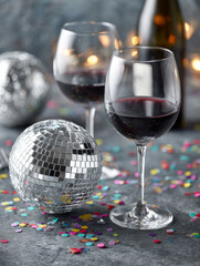 Elegant wine glasses with disco ball and confetti on table