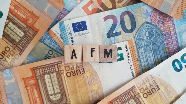 AFM acronym made of wooden letter cubes on pile of Euro banknotes. Autoriteit Financi&euml;le Markten (Financial Markets Authority, overseeing pension products)