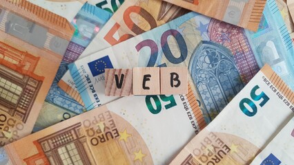 Obraz premium VEB acronym made of wooden letter cubes on pile of Euro banknotes. Vereniging van Effectenbezitters (Dutch Association of Investors)