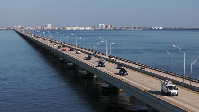 Aerial high-angle perspective of the Gandy Bridge, a major causeway spanning the expansive waters of Tampa Bay. The image follows the steady flow of vehicle traffic on US Highway 92,