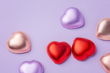Fototapeta premium Heart chocolate with colorful foil wrapped on purple background, valentines day and love concept