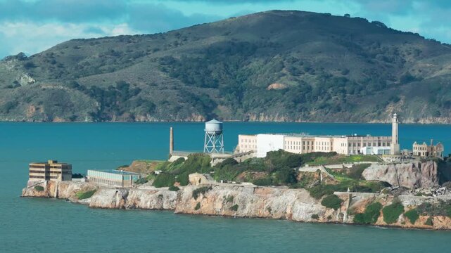 Telephoto aerial dolly shot of Alcatraz Island in San Francisco Bay on a bright blue sky day in Northern California. 4K