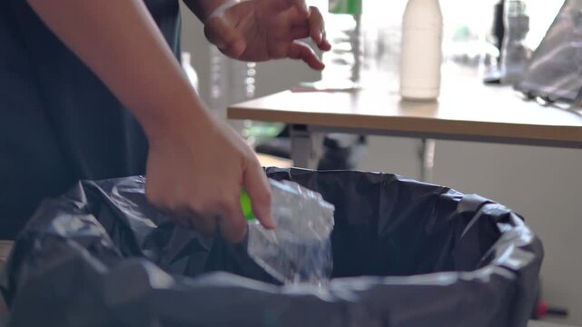 Person placing plastic bottle into recycling bin in modern home. Waste sorting, sustainability and environmental responsibility concept