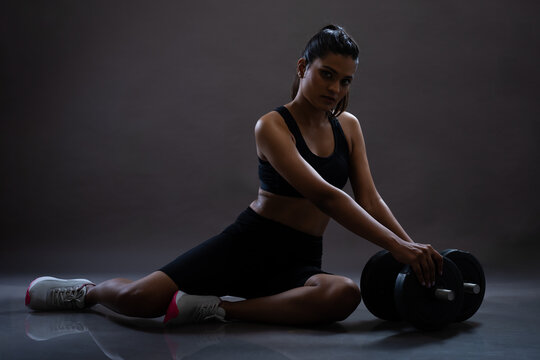 Young girl doing workout in active wear. Low key images. Studio light environment. Fitness freak young girl performing workout. 