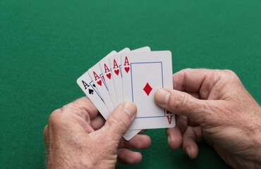 Poker Hand Featuring Four Aces and a Random Card Held Against Green Background