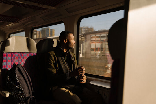 Stylish man with reusable cup inside a train