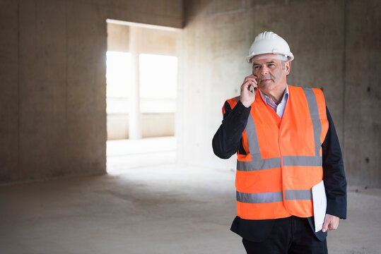 Man on the phone wearing safety vest in building under construction