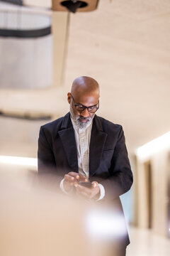Bald mature businessman with grey using cell phone