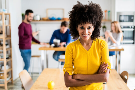 Portrait of smiling woman at dining table at home with friends in background