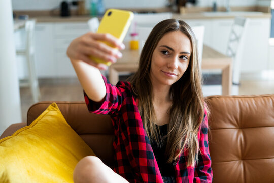 Young woman taking a selfie on a couch at home