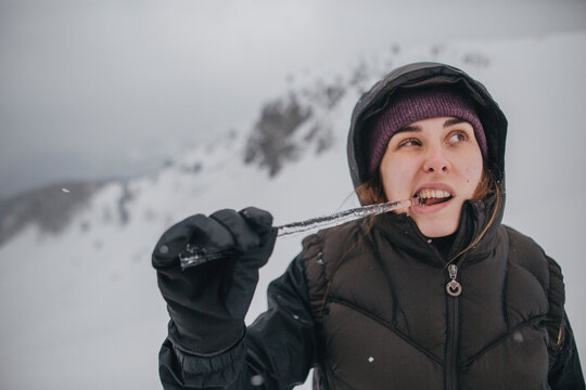 Austria, Kitzbuehel, portrait of young woman biting icicle