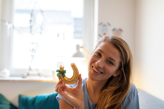 Portrait of smiling young woman at home holding horseshoe