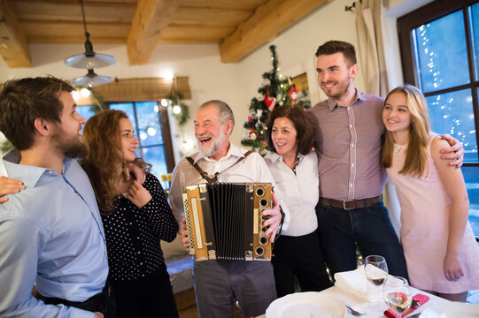 Senior man playing accordion for happy family at Christmas