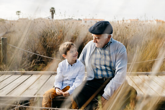 Grandfather sitting with his grandson on boardwalk talking