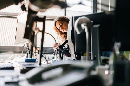 Businesswoman connecting computer cables in office