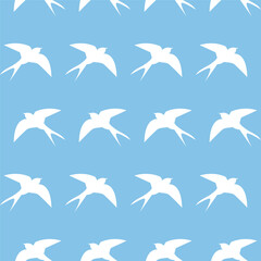 Obraz premium Swallows flying in a repeating pattern on a blue background for a textile design or wallpaper