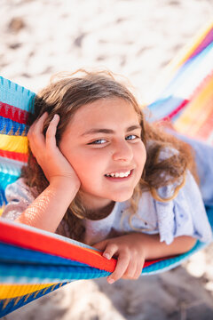 Close up of a girl in a hammock with right hand on head.