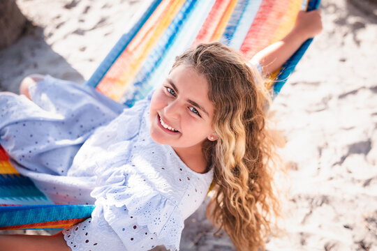 Girl sitting in hammock looking back at camera.
