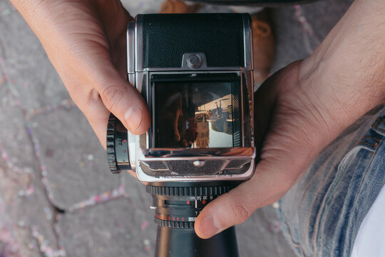Hands holding vintage medium format camera viewing city