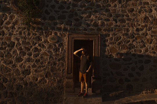 Man standing in doorway shielding eyes from sun