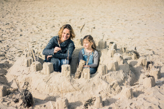 Mother and daughter building a sandcastle on the beach