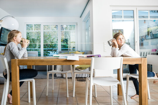 Two girls using tin can phone at table