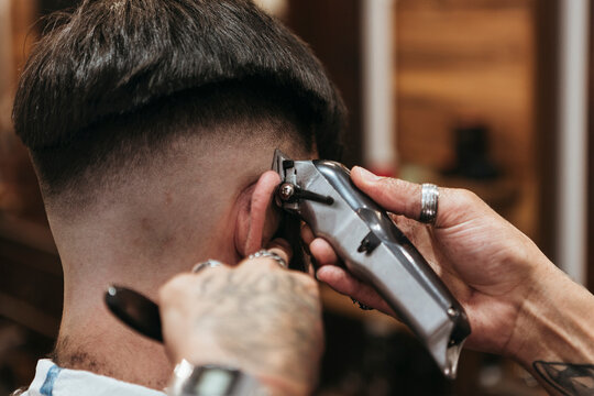 Barber's hands using electric razor on man at hair salon
