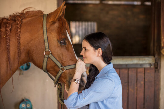 Smiling woman caring for a horse on a farm