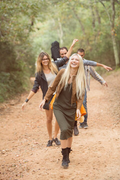 Four happy friends having fun on path in the forest