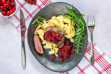 Roasted ostrich loin with cranberry and orange sauce and tagliatelle pasta