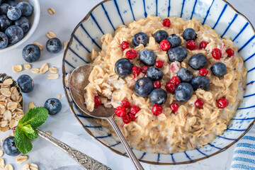 Thick Scottish rolled oats porridge with fresh blueberries and lingonberries