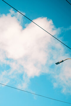 Minimal urban cloudscape with blue sky, white copy space and streetlight silhouette, modern city atmosphere background