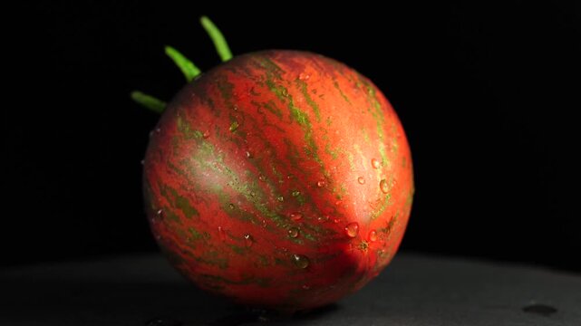 Heirloom tomato rotating slowly, showing skin texture and longitudinal stripes.