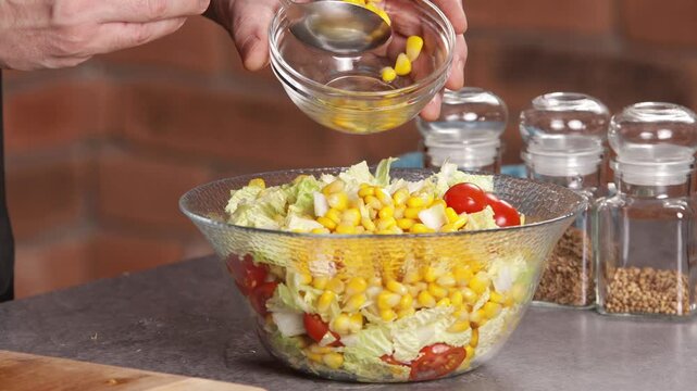 The cook adds cooked canned corn to the bowl and mixes the salad.