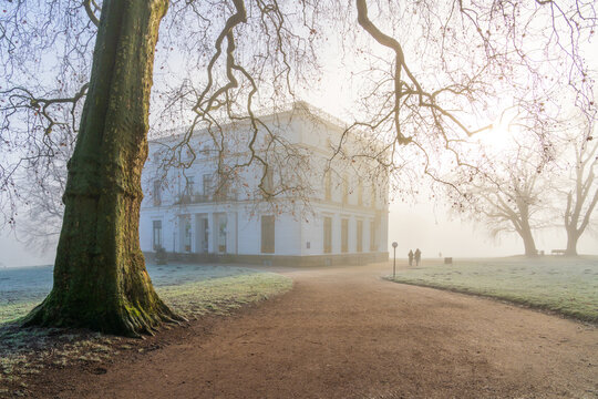 Jenisch Haus shrouded in fog with bare trees and frozen ground at Jenischpark