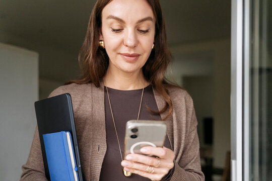 Businesswoman at the office using mobile phone with confident expression