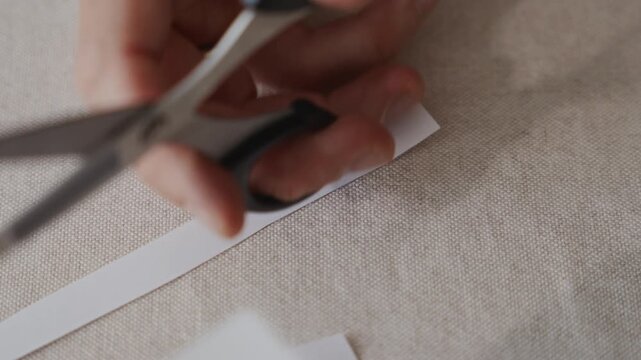 Close up view of scissors cutting paper during craft process. Camera highlights careful hand movement and clean cutting line. High quality 4k footage