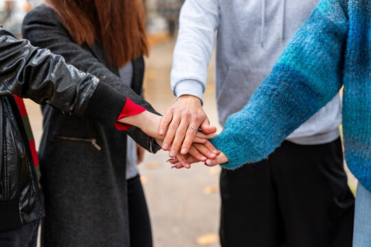 Friends stacking hands outdoors showing teamwork and unity