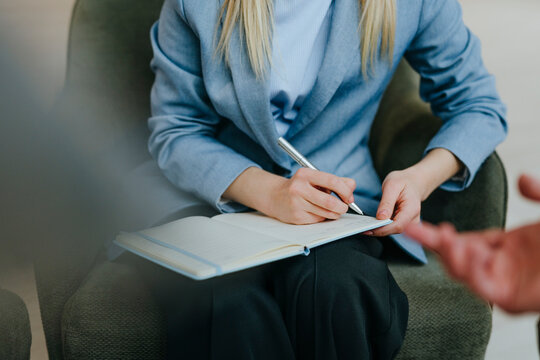 Businesswoman writing in notebook during office meeting close-up