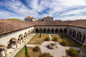Fototapeta premium La Romieu cloister historic architecture featuring well and garden