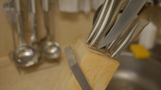 Close-up shot of a hand taking a kitchen knife from a wooden knife block. Everyday cooking preparation, kitchen routine and domestic food preparation concept. High quality 4k footage