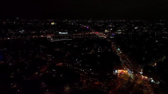 A nocturnal aerial panorama of Paris. The dark silhouette of the city is intersected by glowing streets and prominent points of light on the horizon under a vast night sky.