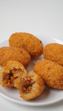 A snack called combro, typical of West Java, Indonesia, made from cassava with oncom chili sauce filling, served on a white plate and placed in a white place (isolated white).