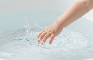 Fototapeta premium Baby's Hand Playing in Water: Creating Splashes and Ripples of Joyful Exploration in Bathtub