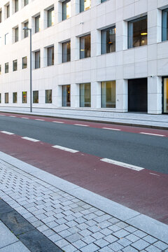 Modern urban road and street beside a building facade with sidewalk lines creating an empty city scene of clean architecture in daylight